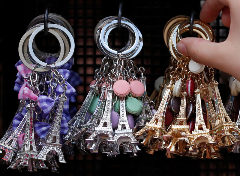 © Reuters. Tourists look at Eiffel Tower keychains displayed in a souvenir shop in Paris