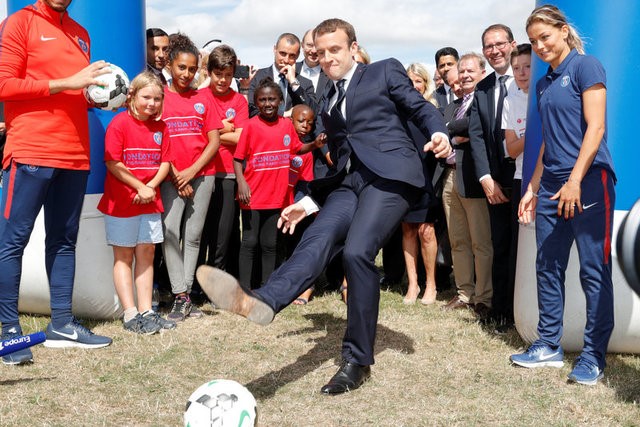 © Reuters. French President Emmanuel Macron kicks the ball as he visits the recreationnal centre for children in Moisson