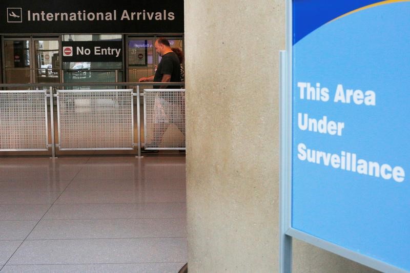 © Reuters. FILE PHOTO: A sign warns of surveillance at the International Arrival area, on the day that U.S. President Donald Trump's limited travel ban, approved by the U.S. Supreme Court, goes into effect, at Logan Airport in Boston