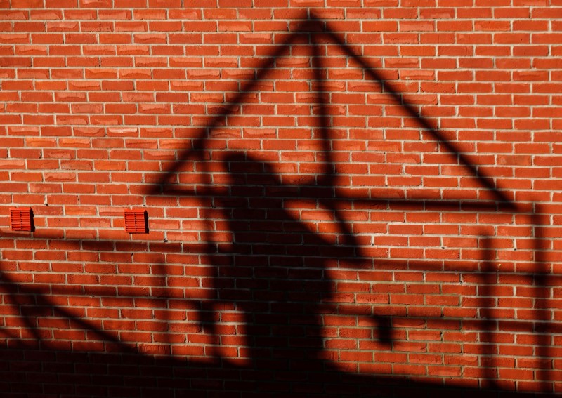 © Reuters. FILE PHOTO: A construction worker casts a shadow as he works on a Taylor Wimpey housing estate in Aylesbury