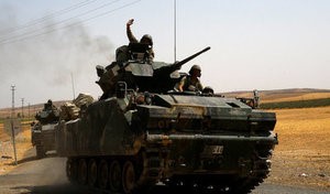 © Reuters. FILE PHOTO: A Turkish soldier on an armoured personnel carrier waves as they drive from the border back to their base in Karkamis on the Turkish-Syrian border