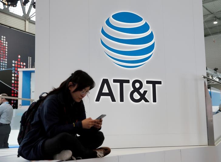 © Reuters. A woman looks at her mobile next to AT&T logo during the Mobile World Congress in Barcelona