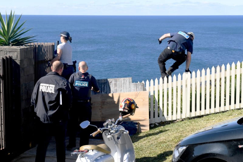 © Reuters. A policeman jumps a fence at the home of John Ibrahim during a police operation in Sydney