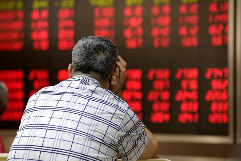 © Reuters. Инвестор в Пекине смотрит на табло с данными о торгах