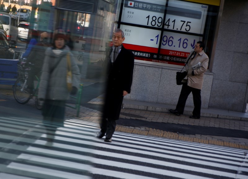 © Reuters. People walk past an electronic board showing stock prices outside a brokerage at a business district in Tokyo