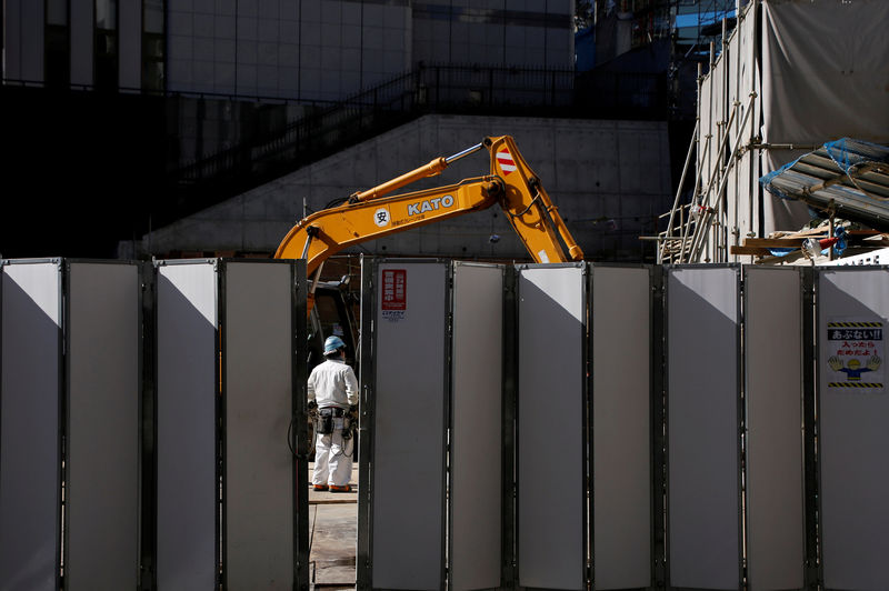 © Reuters. FILE PHOTO: A worker is pictured next to heavy machinery at a construction site in Tokyo's business district