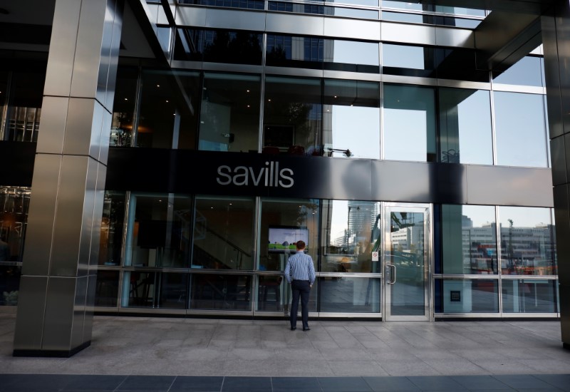 © Reuters. A man looks in the window of a Savills office in Canary Wharf