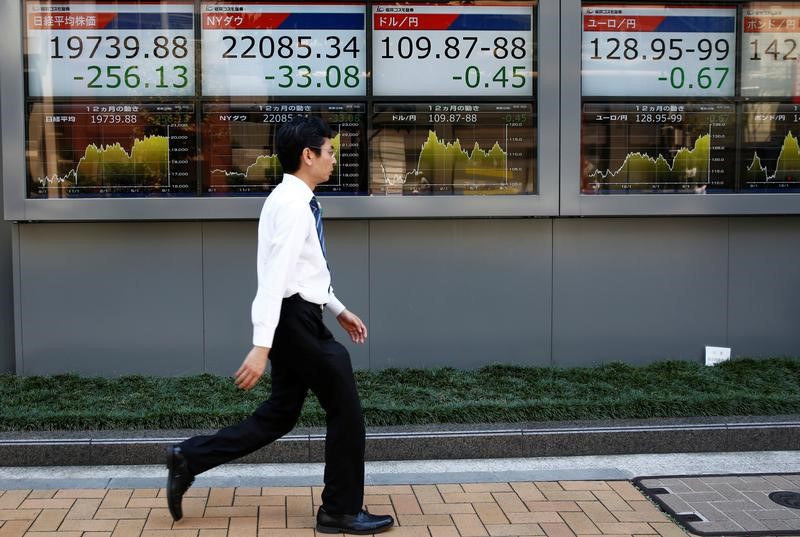 © Reuters. A man walks past electronic boards showing Japan's Nikkei average, the Dow Jones Industrial Average and foreign exchange rates outside a brokerage at a business district in Tokyo