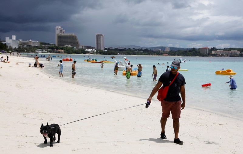 © Reuters. A tourist walks his dog along Tumon beach on the island of Guam