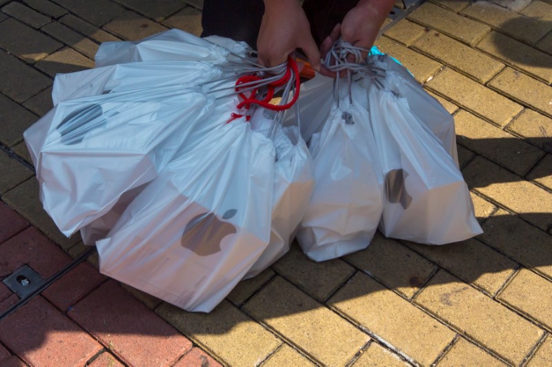 © Reuters. FILE PHOTO: A man places collects bags containing the newly released iPhone 6, outside an Apple store in Hong Kong