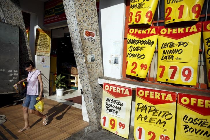 © Reuters. Mulher passa por cartazes de preços, do lado de fora de mercado no Rio de Janeiro