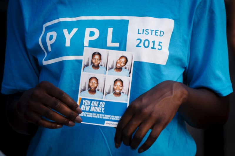 © Reuters. FILE PHOTO: A Paypal employee holds photographs of herself during celebrations for the company's relisting on the Nasdaq in New York