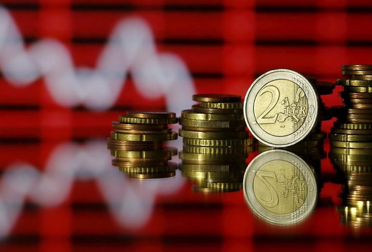 © Reuters. Монеты евро на фоне графика
