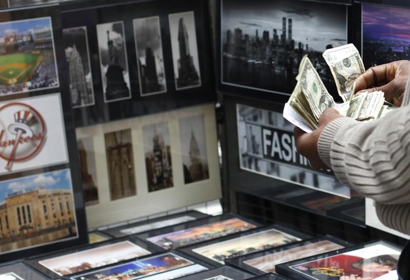 © Reuters. FILE PHOTO: A vendor counts money at his photograph stand at Times Square in New York