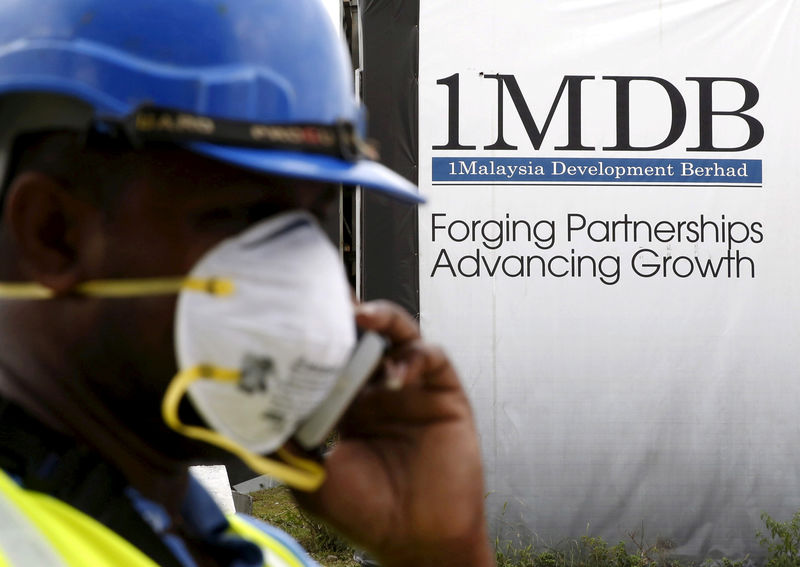 © Reuters. FILE PHOTO: A construction worker talks on the phone in front of a 1Malaysia Development Berhad (1MDB) billboard at the Tun Razak Exchange development in Kuala Lumpur, Malaysia