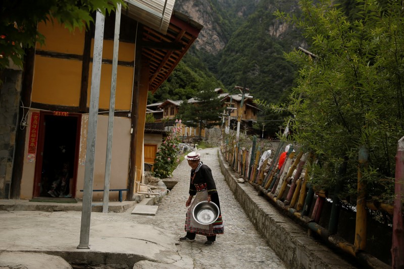 © Reuters. A woman in traditional clothes walks in a Tibetan village in Jiuzhaigou county