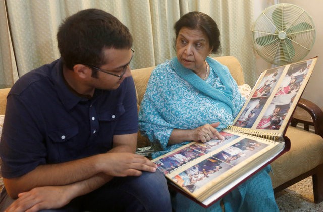 © Reuters. Rehana Khursheed Hashmi, 75, migrated from India with her family in 1960 and whose relatives, live in India, speaks with her grandson Zain Hashmi, 19 while looking family photo album at her residence in Karachi,