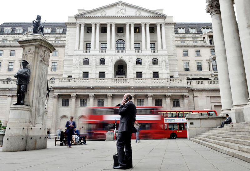 © Reuters. FILE PHOTO - A man talks on a mobile phone as people walk past the Bank of England, in London
