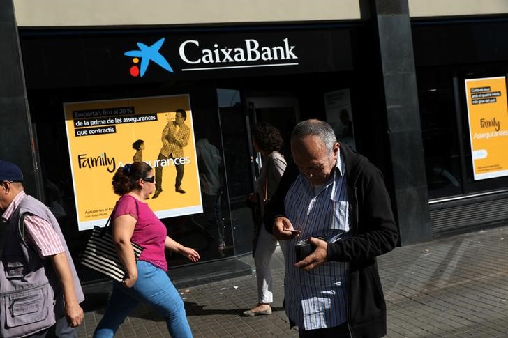 © Reuters. Homem coloca dinheiro na carteira em frente a uma agência do CaixaBank em Barcelona, Espanha