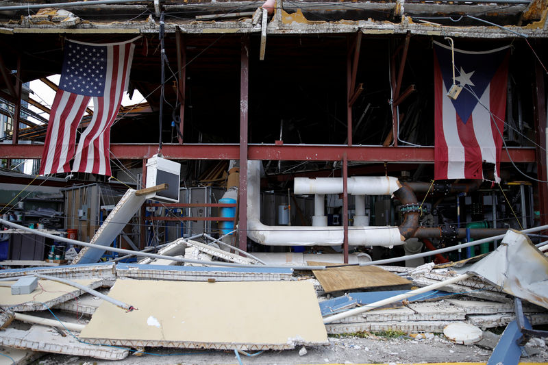 © Reuters. U.S. and Puerto Rico flags hang on a damaged church after the area was hit by Hurricane Maria in Carolina