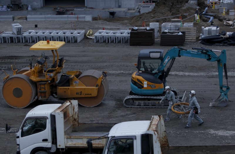 © Reuters. People work next to heavy machineries at a construction site in Tokyo