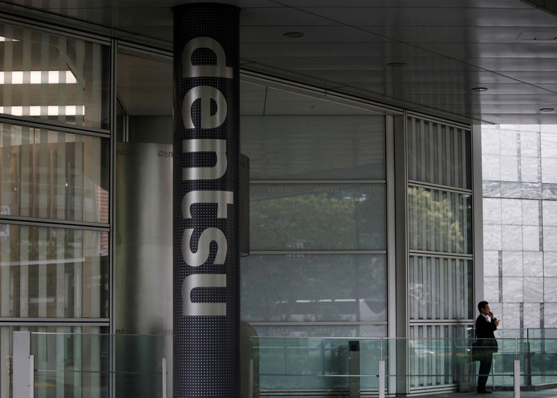 © Reuters. FILE PHOTO: A man speaks on his mobile phone near a logo of Dentsu Co. at the entrance of the company headquarters in Tokyo
