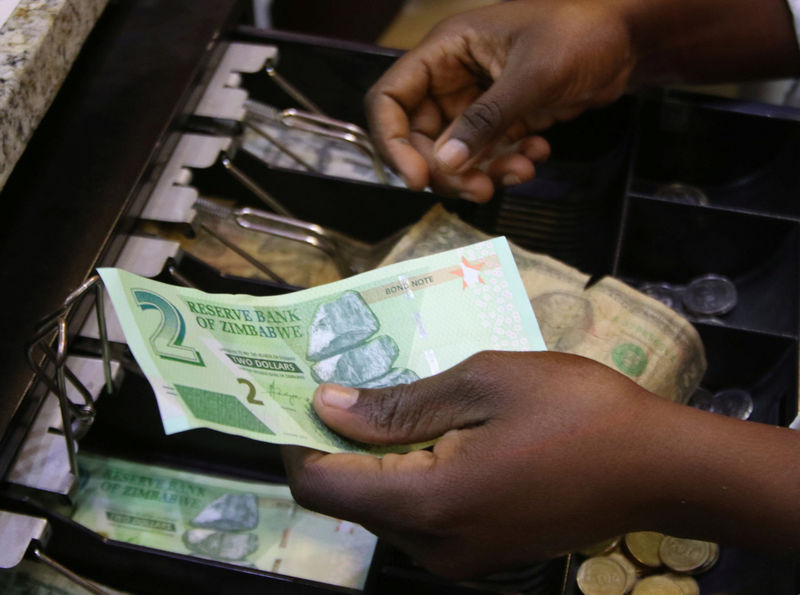 © Reuters. FILE PHOTO: A till operator collects new bond notes from a shopper at a supermarket in the capital Harare