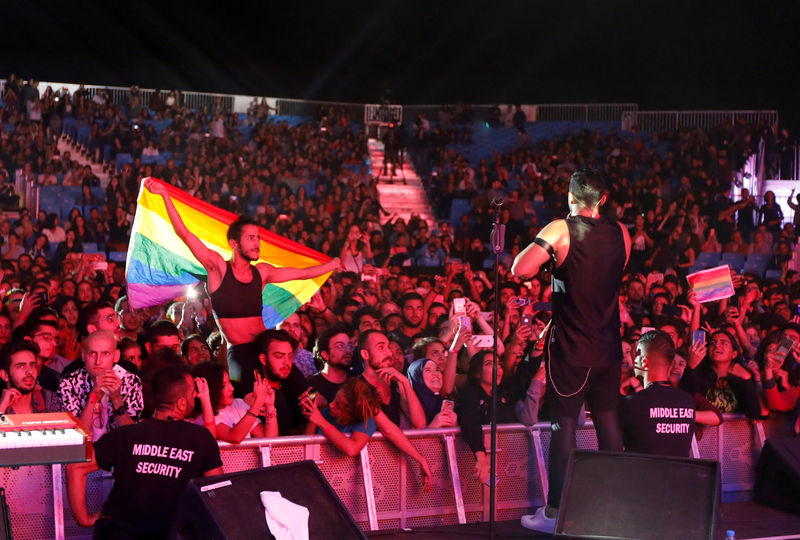 © Reuters. FILE PHOTO:A fan of Lebanese alternative rock band Mashrou' Leila holds a rainbow flag during their concert at the Ehdeniyat International Festival in Ehden town