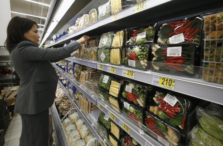 © Reuters. Сотрудник магазина Ашан раскладывает продукты по полкам