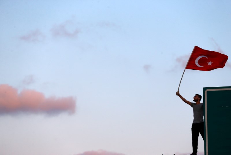 © Reuters. A man waves a Turkey's national flag as he attends a ceremony marking the first anniversary of the attempted coup at the Bosphorus Bridge in Istanbul