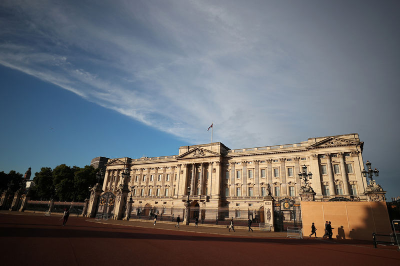 © Reuters. People walk past a protective board outside Buckingham Palace in London