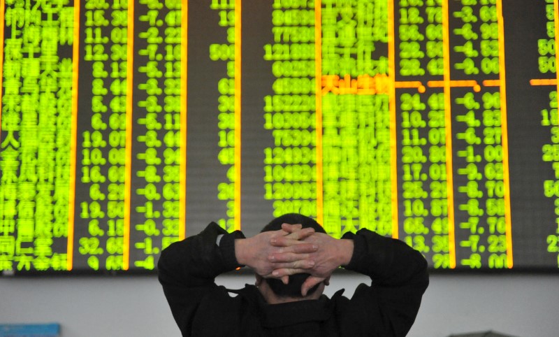 © Reuters. FILE PHOTO: An investor looks at an electronic screen at a brokerage house in Hangzhou
