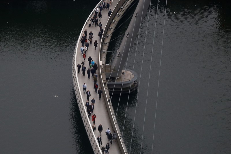 © Reuters. People cross a bridge in the Canary Wharf financial district in London