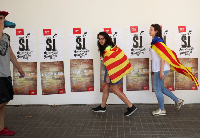 © Reuters. People wear Esteladas (Catalan separatist flags) as they past pro independence posters from a youth branch of the leftist Esquerra Republicana de Catalunya political party during the regional national day 'La Diada' in Barcelona