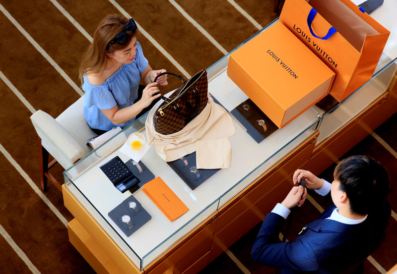 © Reuters. FILE PHOTO: A woman buys a Louis Vuitton bag in a shop in Singapore