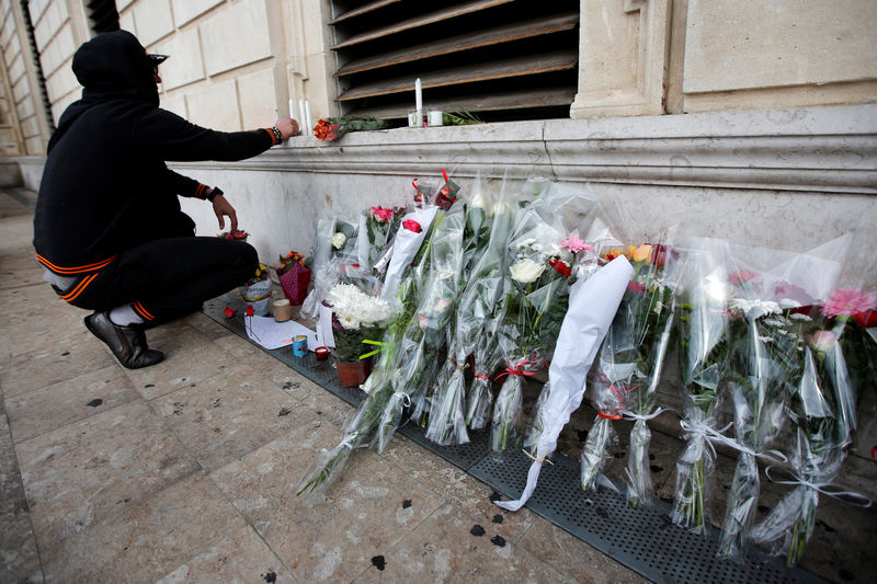 © Reuters. A man installs candles in tribute to the two women who were stabbed to death by a knife attack at the main train station in Marseille