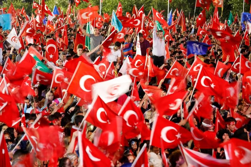 © Reuters. FILE PHOTO: People wave Turkey's national flags as they attend a ceremony marking the first anniversary of the attempted coup in front of the Turkish Parliament in Ankara