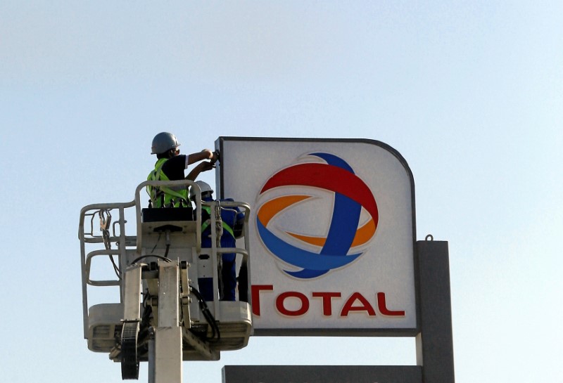 © Reuters. Workers fixing the logo for oil giant Total is seen at a petrol station in Cairo
