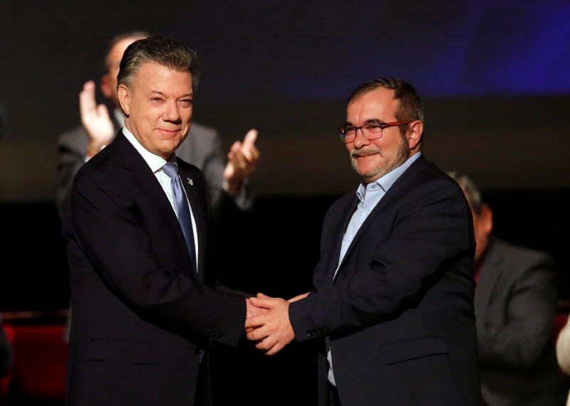 © Reuters. Colombia's President Juan Manuel Santos and Marxist FARC rebel leader Rodrigo Londono known as Timochenko shake hands after signing a peace accord in Bogota