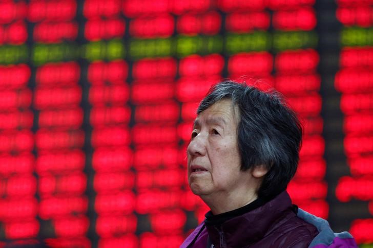 © Reuters. An investor looks at an electronic board showing stock information on the first trading day after the New Year holiday at a brokerage house in Shanghai