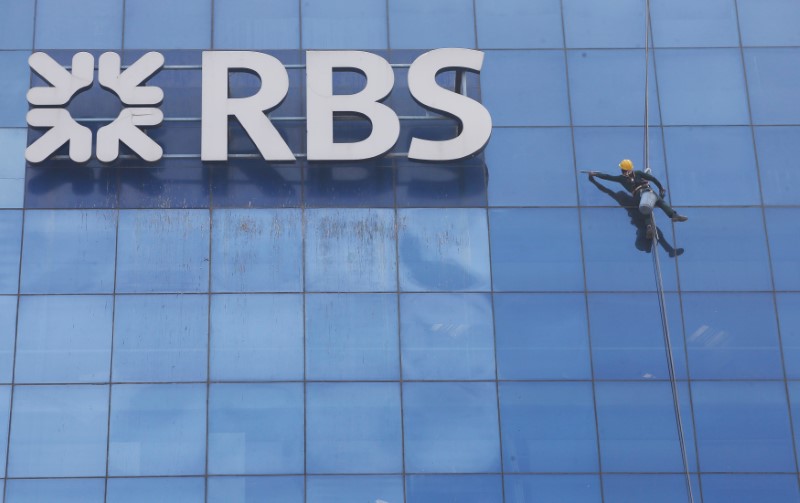© Reuters. Worker cleans the glass exterior next to the logo of RBS (Royal Bank of Scotland) bank at a building in Gurugram