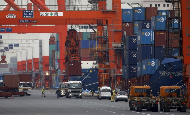 © Reuters. Workers load containers onto trucks from a cargo ship at a port in Tokyo