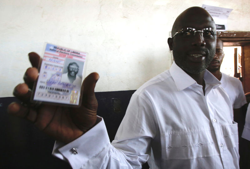 © Reuters. Weah, former soccer player and presidential candidate of CDC shows his voter's card in Monrovia