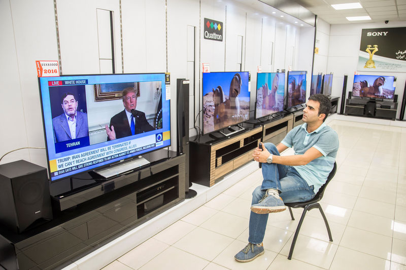 © Reuters. Man watches a TV broadcast of U.S. President Donald Trump's speech, in Tehran