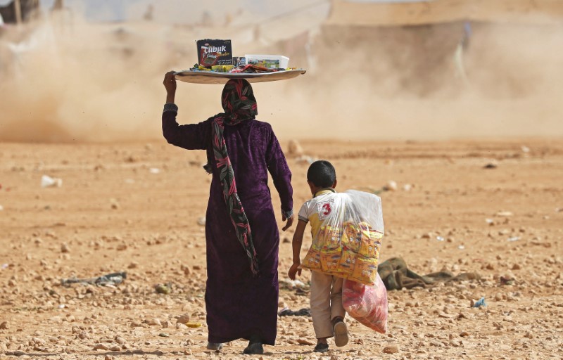 © Reuters. A mother and a child sell foodstuff at a refugee camp for people displaced in fightings between the Syrian Democratic Forces and Islamic State militants in Ain Issa