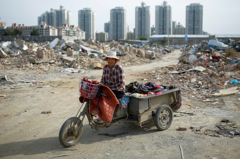 © Reuters. Migrant worker Wang Qin sits on her tricycle that she uses to transport collected scrap materials in a neighbourhood of demolished buildings at the outskirts of Beijing