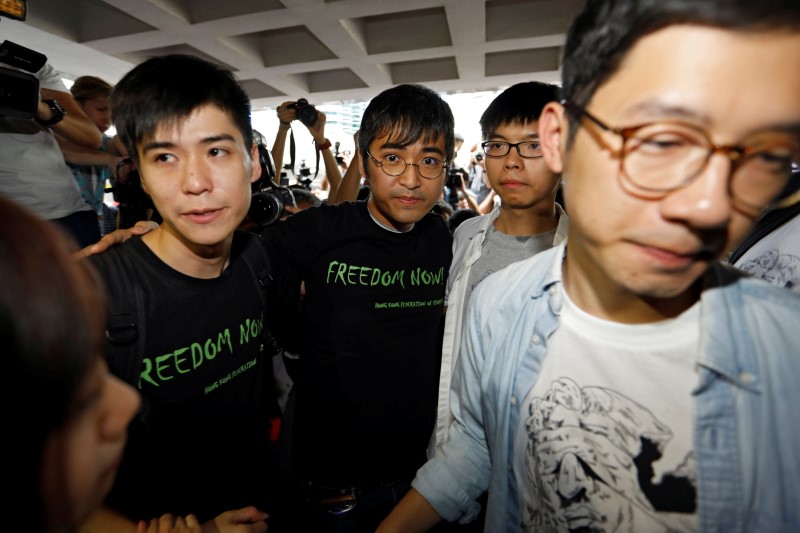 © Reuters. Student leaders Lester Shum, Alex Chow, Joshua Wong and Nathan Law hold hands as they walk into the High Court to face verdict on charges relating to the 2014 pro-democracy Umbrella Movement, in Hong Kong