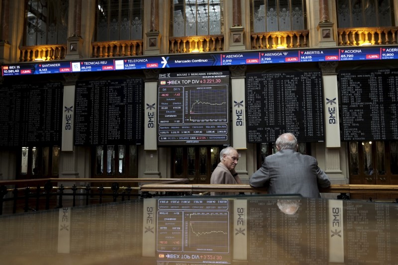 © Reuters. Traders talk as they are seen near screens at Madrid's bourse, Spain