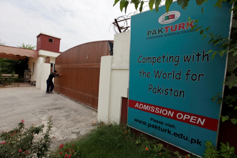 © Reuters. FILE PHOTO - A man closes the main gate of PakTurk International Schools and Colleges in Islamabad