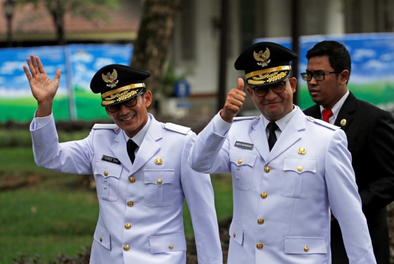 © Reuters. Jakarta Governor Anies Baswedan and his deputy Sandiaga Uno wave to reporters before a swearing-in at the Presidential Palace in Jakarta